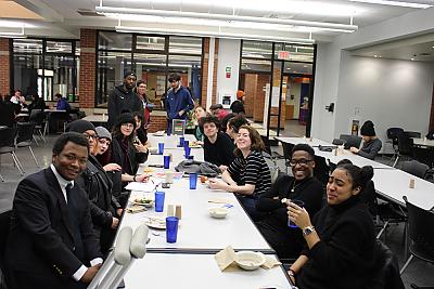 A long table shot of students who participate in Center for Diversity and Inclusion programming gathering for dinner in the Dining Hall. 
