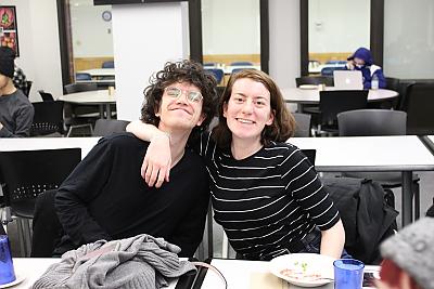 A female student and a male student smile for the camera during a dinner for students who participate in Center for Diversity and Inclusion activities. The female student on the left has her arm around the male student. 
