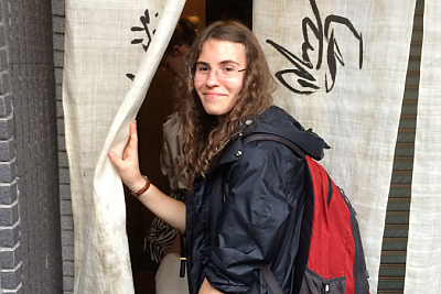 Student Jenny Beller entering building through a curtain in Japan